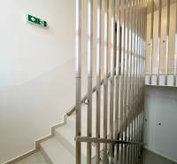 A staircase with a railing and an emergency exit sign in a 2-room apartment.