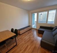 Living room with a corner sofa, dining table, and wooden decor flooring in a 2-room apartment.