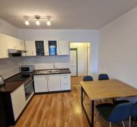 A kitchen in a 2-room apartment with a wooden decor floor, a table with chairs.