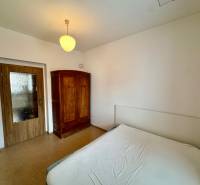 Bedroom in a 2-room apartment with white walls, wooden doors, and a wardrobe.