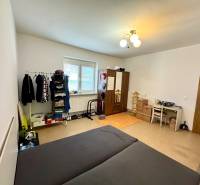 A room in a two-room apartment with a bed, a wardrobe, and a desk.