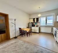 A kitchen in a 2-room apartment with a kitchen table and a floor with a wooden decor.