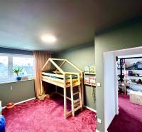 Children's room in a family house with a wooden bed and a burgundy carpet.