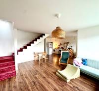 Living room with wood-patterned flooring, staircase, and kitchen in a family house.