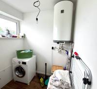Laundry room in a family house with a washing machine, boiler, and floor with wooden decor.