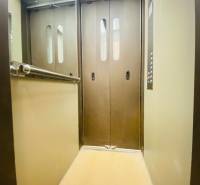An elevator with metal doors and a mirror, lights on the ceiling.
