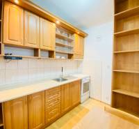 A kitchen in a 2-room apartment with wooden decor furniture and flooring.
