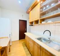 A kitchen in a 2-room apartment with a wooden decor floor and wooden furniture.