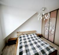 A bedroom in a 3-room apartment with a bed, built-in wardrobe, and floor with a wooden decor.
