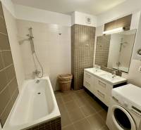 Bathroom with a bathtub, double sink, and washing machine in a 3-room apartment.
