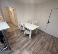 A one-room apartment with a wooden decor floor and a dining table.