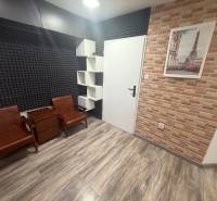 Izba s podlahou s dreveným dekorom a tehlovým obkladom, zariadená sedacím nábytkom.