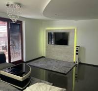 Living room in a family house with a glossy floor and a TV on the wall.