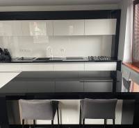 A kitchen in a family house with glossy black and white furniture and a dining counter.