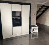 A kitchen in a family house with a glossy black floor and white appliances.