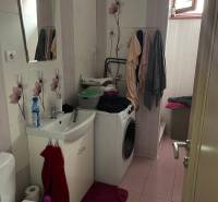 A bathroom in a family house with sanitary fixtures, a washing machine, and floral tiles.