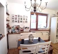 A dining room in a family house with white furniture, pictures on the wall, and a decorative chandelier.