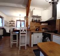The kitchen and living room in a family house with a wooden decor floor and white furniture.