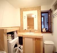 Bathroom of a family house with a washing machine, sink, and open window.