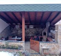 Stone terrace of a family house in Vršatské Podhradie with a fireplace and wooden roofing.