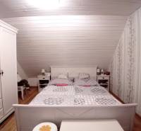 Attic bedroom in a family house with floral wallpaper and wood-patterned flooring.
