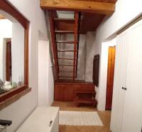 Interior of a family house with a wooden staircase, tiles, and white cabinets.