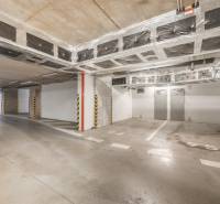 Underground parking lot with available parking spaces, lighting, and concrete surface.