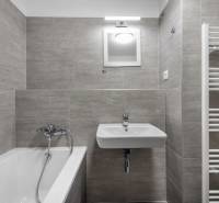 Bathroom of a 2-room apartment with a bathtub, sink, and ladder radiator.