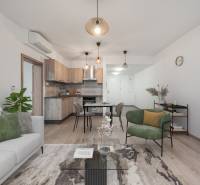 Living room with a kitchenette in a 2-room apartment with a wooden decor floor and comfortable seating.
