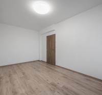 An empty room with wood-patterned flooring in a two-room apartment.