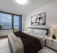 Bedroom in a 2-room apartment with a comfortable bed, a painting, and a lamp on the nightstand.