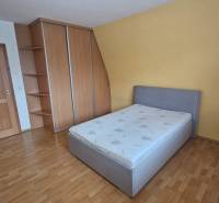 A bedroom with a wood-decor floor in a 3-room apartment, equipped with a bed and a built-in wardrobe.
