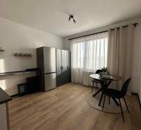 A kitchen with a wood-patterned floor and a table in a studio apartment.