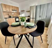 A kitchenette in a studio apartment with a wooden decor and a round table.