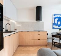 A kitchen with a wood-patterned floor, wooden cabinets, and a dining table in a three-room apartment.