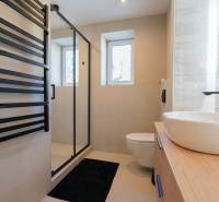 A bathroom in a 3-room apartment with a black ladder radiator and a glass shower enclosure.