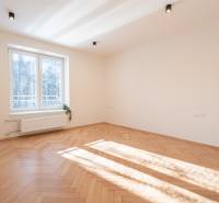 A bright room in a 3-room apartment with a wood-patterned floor and a large window.