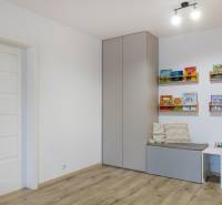 Children's room with a wooden decor floor, a cabinet on the wall, and bookshelves.