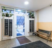 Entrance hall of an apartment building in Nitra with a bench and mailboxes.