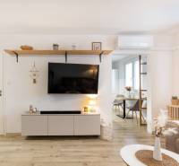 Living room in a two-room apartment with a television, wooden decor flooring.