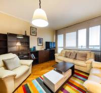 Living room in a 3-room apartment with sofas, a colorful carpet, and a wooden decor floor.