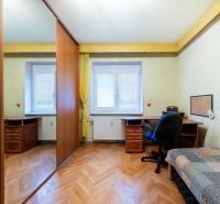 A room with a wood-patterned floor, a table, and a wardrobe in a three-room apartment.