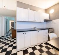 A kitchen in a 3-room apartment with black and white flooring, white cabinets, and a stove.