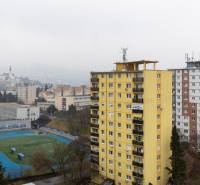 View of Nitra from Štúrová with 3-room apartments, a yellow panel building, and a sports field.