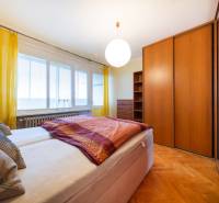 A bright bedroom with a large bed and a wardrobe in a three-room apartment, with a wooden decor floor.