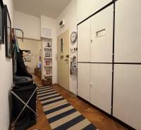 A hallway in a 2-room apartment with a wooden decor floor and storage cabinets.