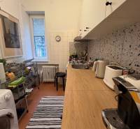 Kitchen in a 2-room apartment with a wooden decor floor, a washing machine, and a coffee maker.