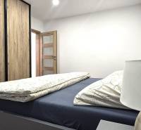 A bedroom with a bed, a wardrobe with a wooden decor, and a lamp in a 3-room apartment.