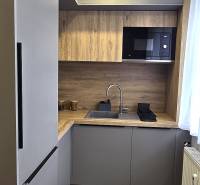 A kitchen in a 3-room apartment with a wooden decor floor, built-in microwave.