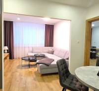 Living room of a three-room apartment with a sofa, table, and floor with a wooden decor.